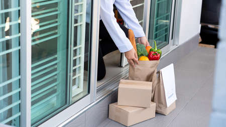 Lifestyle concept A wife house picking the bag full of the colorful vegetable delivered during her quarantine.の写真素材
