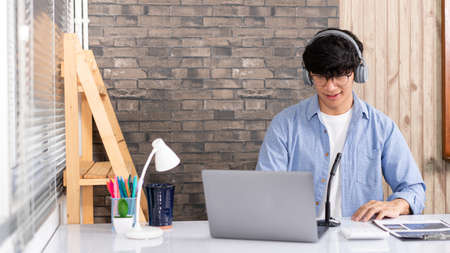 Educational concept A young male teacher looking at webcam and teaching online lesson by video conference call on a computer during the coronavirus outbreak.の写真素材