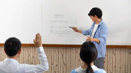 Educational concept a young smart male teacher explaining decision of hard math in a classroom before Covid-19 epidemic.の写真素材