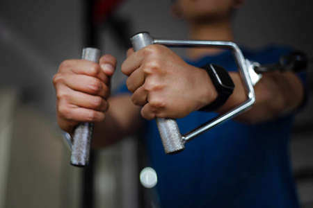 Training gym concept a muscled male teenager using a gym equipment repeating pushing forward for developing his breast.の写真素材
