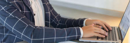 Business partners concept a young businessman using a laptop revising annual sales summary.