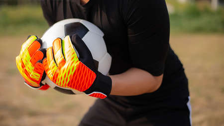 Sports and recreation concept a young male goalkeeper using his both hands catching the ball as preventing the opposing team from scoring.の写真素材