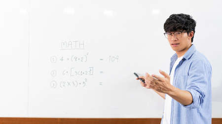 Educational concept a young smart male explaining decision of hard math in a classroom before...