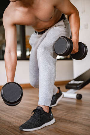 Training gym concept a young adult using his muscular strong arm lifting a dumbbell upward and downward in the gym.の写真素材