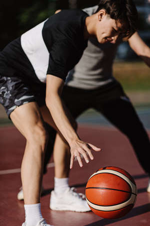 Sports and recreation concept two male basketball players enjoying playing basketball together on the sports ground.の写真素材