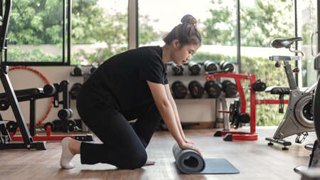 Training gym concept a female teenager using her  arm lifting a dumbbell upward and downward in the gym.の写真素材