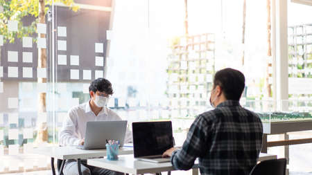 Concept two businessmen wearing a mask planning for new project maintaining social distancing