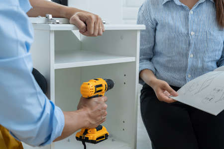Mechanic concept two officers assembling furniture together, preparing for their new office.の写真素材