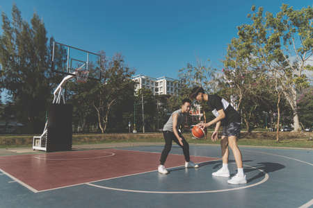 Sports and recreation concept young male teenagers practicing dribbling basketball in the court after school.の写真素材
