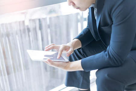 Business partners concept a young businessman wearing navy suit jacket looking on the tablet screen checking an email inbox.の写真素材