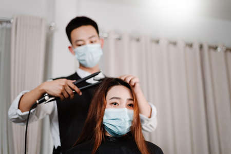 Hair salon concept both male hairstylist and female customer wearing a protective face masks during haircut process.の写真素材
