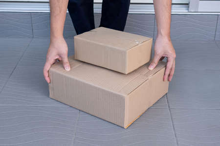 E-commerce concept a man leaving home and lifting the boxes for sending them to his customers via...
