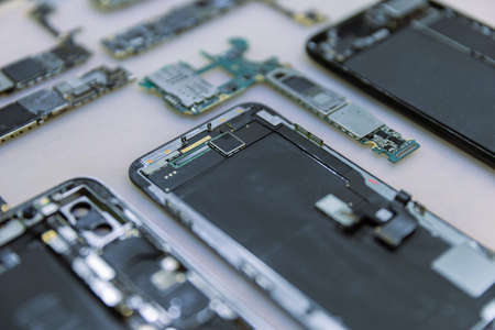 Phone repair concept several electronic devices taken apart into the components like the covers,...