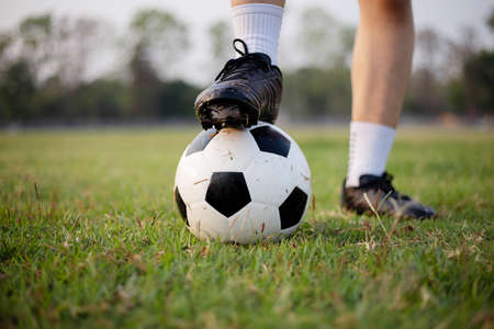 Sports and recreation concept a male soccer player wearing black t-shirt and pants practicing kicking the ball in the grassy field.の写真素材