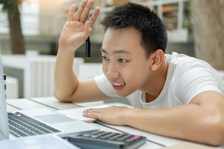 Online studying concept a male student studying from online classroom by using his new white laptop...