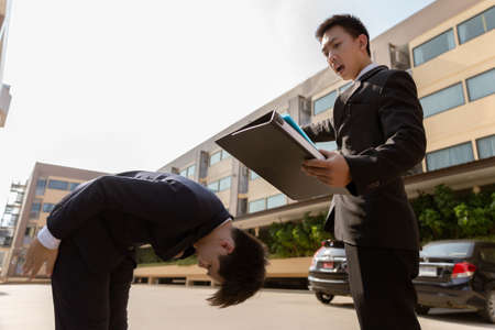 Businessman concept the male boss in black suit with anger firing his employee after committing mistakes for many times in front of the office building.の写真素材