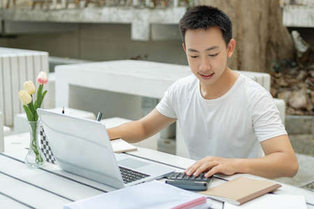 Online studying concept a male student in white t-shirt enjoying studying online and sitting in...