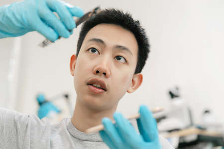 Phone repair concept a young male repairman looking carefully at the parts of the smartphone then assembling them together.の写真素材