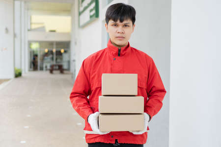 Parcel delivery concept the mailman standing, holding three boxes of parcels, and waiting to distribute them to the customers.の写真素材