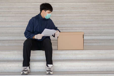 Parcel delivery concept the black hair mailman sitting on the staircase holding checklist and...