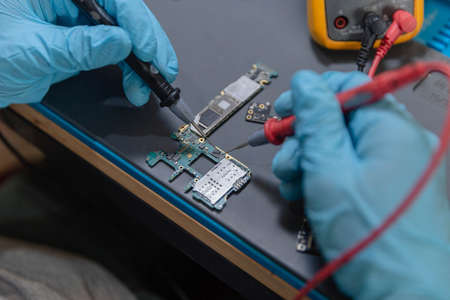 Phone repair concept a young electrical technician using an ammeter measuring the current in a...