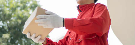 Parcel delivery concept the mailman wearing red uniform and gloves from some logistic companies...