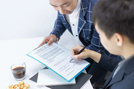 Business partners concept a young male entrepreneur signing a signature on the contract with a big company.の写真素材