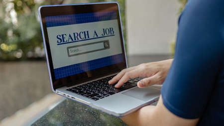 Online studying concept the pale hand of a man trying to type on laptop keyboard for searching the definition of a few words that he cannot understand.の写真素材
