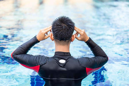 Sports and recreation concept a male youth starting to swim in a blue-sky swimming pool.