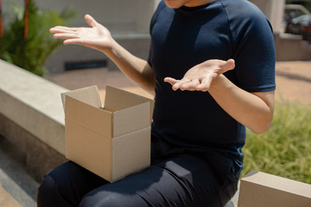 Parcel delivery concept the male teenager looking awkward when finding that the inside of the parcel ordered from an online store is empty.の写真素材
