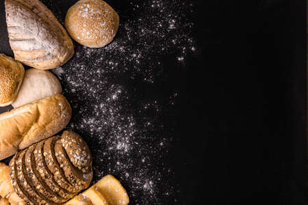 bread concept several slices of dark brown bread with seeds, buns, croissants, and loaves of bread...