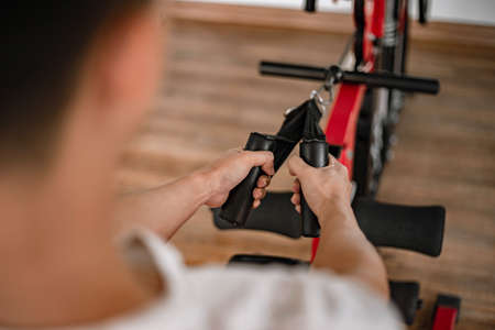 Training gym concept a male teenager using a gym equipment pulling his both muscular arms against the machine.の写真素材
