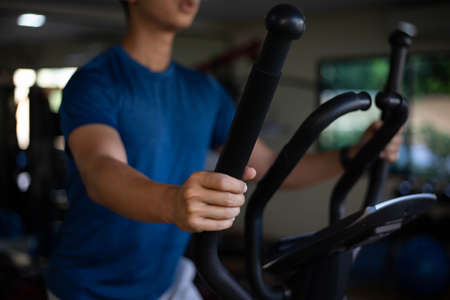Training gym concept a male teenager doing cardio workout on cycling machine in the gym as his healthy routine.の写真素材