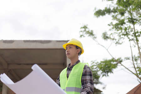 engineer concept The constructing manipulator who wears a hard yellow hat, dark-toned plaid blouse...
