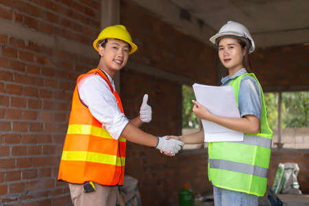 engineer concept The male engineering worker who wears oranges uniform shaking hand with the female...