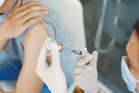 Vaccination concept, Male doctor preparing vaccine against covid-19 to injecting for male patient.