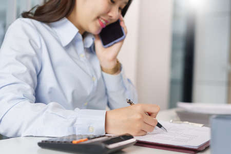 Business concept, Businesswoman talking with partners on phone to checking information on document.の写真素材