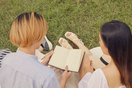 picnic concept The couple perching on the ground together and surveying the notebook that they brought with on the picnic.の写真素材