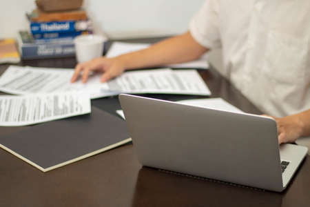 Remote work concept, Male freelancer is reading business data on document while working at home.