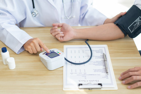Visiting a doctor concept A doctor sitting using the tool to measure blood pressure on the patientâs arm carefullyの写真素材