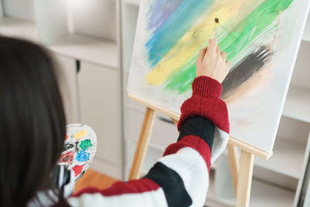 The art concept, Asian female artist using paint brush and color palette to painting on canvas.の写真素材