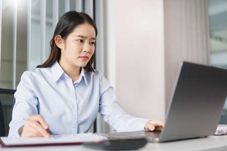 Business concept, Businesswoman checking financial data on laptop and taking notes on document.の写真素材