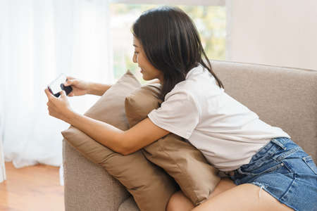 Cozy lifestyle concept, Young woman sitting on couch and use smartphone to watching movie at home.