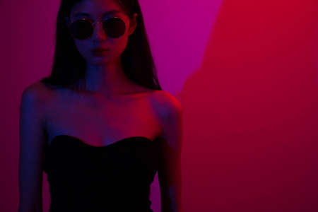 Fashion and beauty concept, Fashion woman with glitter makeup wear sunglasses on neon background.