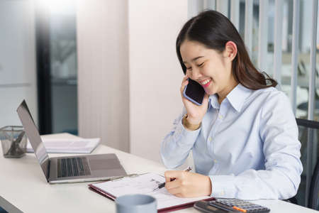 Business concept, Businesswoman talking with partners on phone to checking information on document.の写真素材