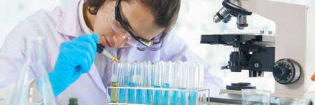 Laboratory research concept, Scientist working in lab to drop of solution into tube for research.