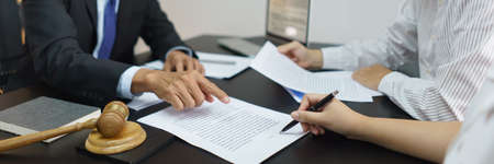 Concept of lawyer counseling, Couple signing divorce contract after senior lawyer explains details.の写真素材