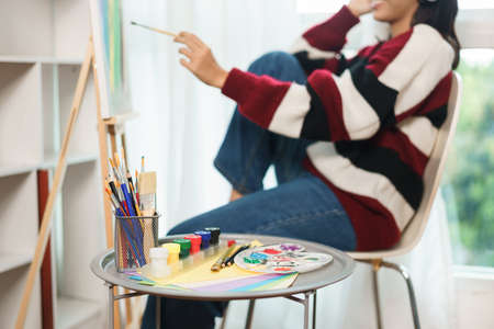 The art concept, Asian female artist with headphone listening music and painting artwork on canvas.の写真素材