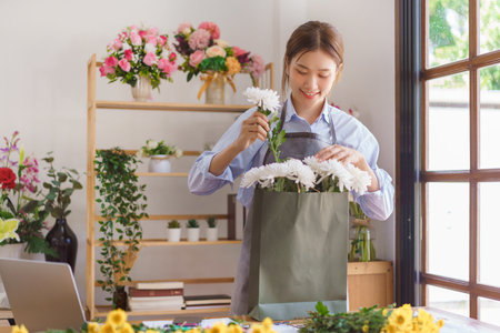 Florist concept, Woman florist arranged bouquet white chrysanthemum in paper bag at flower shop.の写真素材
