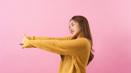 Young woman standing to stretching arms to exercise with happiness isolated on pink background.の写真素材